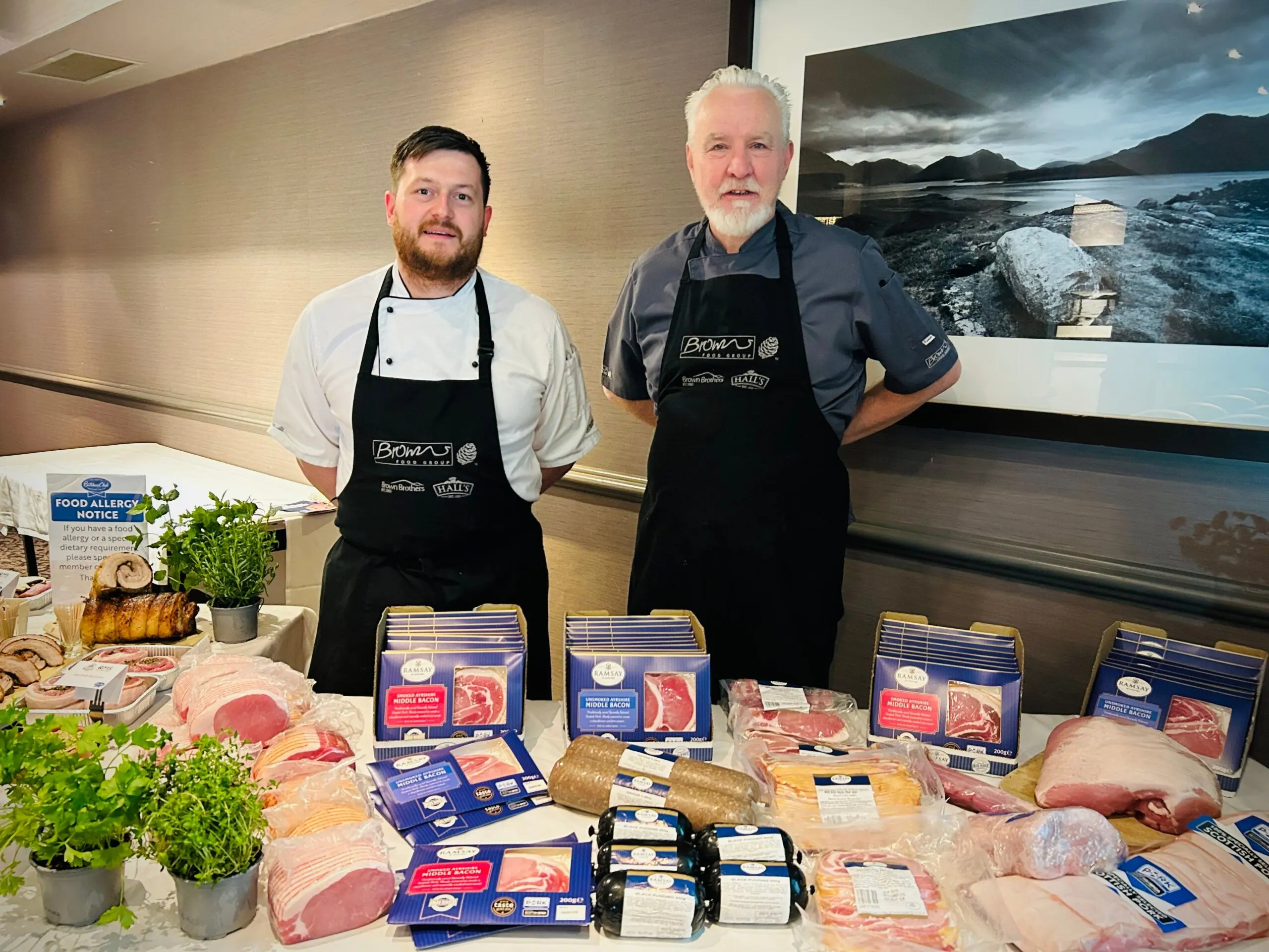 Two Browns chefs behind a display of Scottish pork products and packs at a QMS event, June 2025